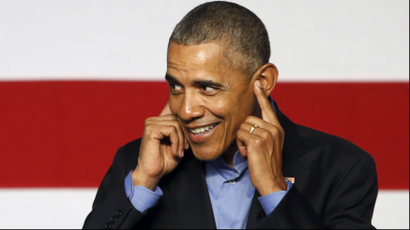 President Obama smiles and puts his fingers in his ears.