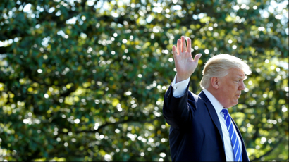 US president Donald Trump waves from a garden