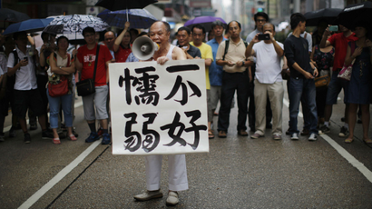 A man in Mong Kok holds up a sign encouraging democracy protesters, "Don't be weak."
