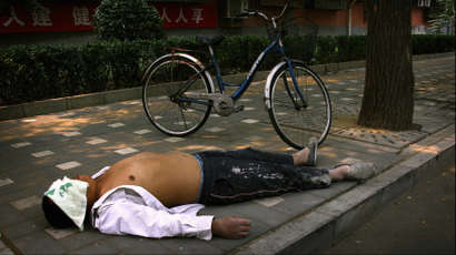A man sleeps next to his bicycle on a footpath along a Chinese alley known as a "Hutong'', during a hot day in central Beijing June 21, 2012. REUTERS/David Gray