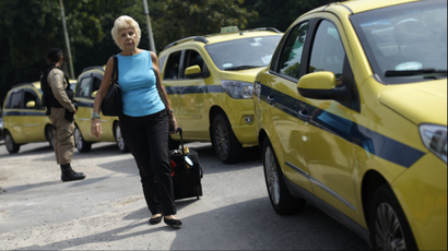 A passenger walks near taxis parked on the access of the Santos Dumont airport during a protest against the online car-sharing service Uber in Rio de Janeiro, Brazil