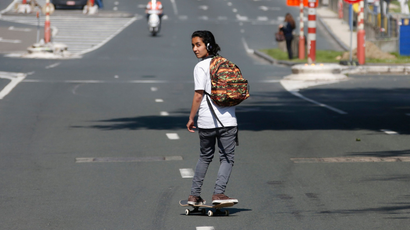 A girl skateboards on a street that was cleared by authorities during a protest against austerity measures by public sector workers, employees and trade union members in central Brussels