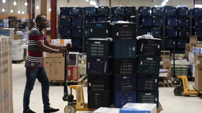 A man pushing a cart stacked with items in a warehouse