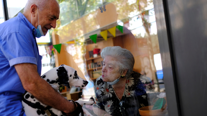 Maria de Concepcion Illa, 89, who lives in a care home, blows a kiss to Menta, the dog of her neighbour Antoni (L), 70, as they talk through a glass front at the Centre Parc nursing home after Catalonia's regional authorities announced restrictions to contain the spread of the coronavirus disease (COVID-19), in Barcelona, Spain