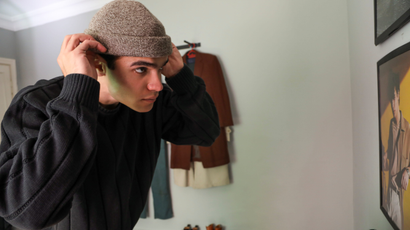 Jordanian fashion A man adjusts his hat while looking in the mirror in his room,