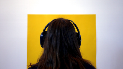Photo of a female wearing headphones looking at a yellow square