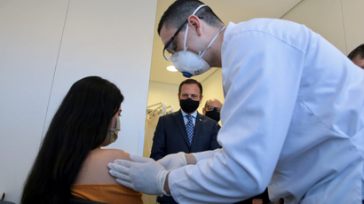 A volunteer receives the first test of the China's Sinovac coronavirus potential vaccine from a healthcare worker as Sao Paulo's Governor Joao Doria looks on amid the coronavirus disease (COVID-19) outbreak, at Hospital das Clinicas, in Sao Paulo, Brazil July 21, 2020.