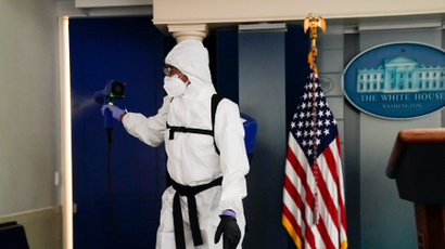 A member of the White House cleaning staff sprays the press briefing room the evening of U.S. President Donald Trump's return from Walter Reed Medical Center