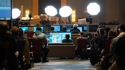 Photo from the Awesome Games Done Quick charity event. The shot is from an aisle in a large conference room where everyone is watching folks play video games for the event.