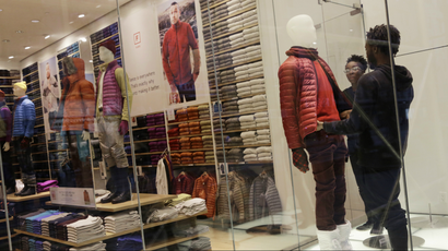 Store employees arrange a mannequin in a Uniqlo display window, Monday, Nov. 18, 2013 in New York. (AP Photo/Mark Lennihan)