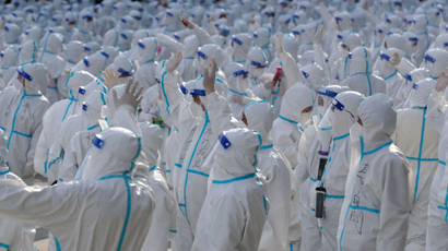 Medical workers in protective suits wave at Changchun residents during a farewell ceremony