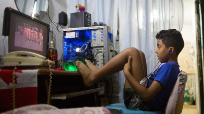 Kevin Lachaise, 8, watches a recorded TV show through the screen of a computer at the living room of his home in downtown Havana February 10, 2015.