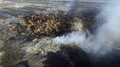 An aerial picture shows smoke rising from the debris among shipping containers at the site of Wednesday night's explosions at Binhai new district in Tianjin, China, August 15, 2015.