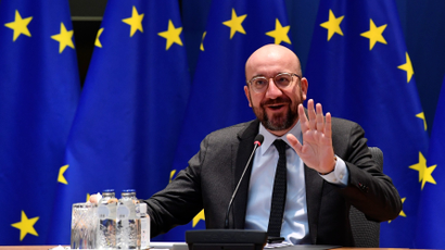 European Council President Charles Michel waves in front of an EU flag.