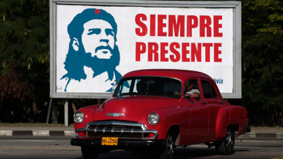 A car is driven beside a billboard with the image of revolutionary leader Guevara in Havana