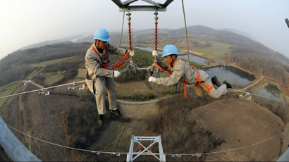 Workers check on electricity pylon situated amid farmlands in Chuzhou, Anhui province.