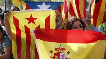 A Spanish unionist supporter holds a Spanish flag beside Catalonian separatist supporters holding estelada flags in front of Catalonia's Parliament in Barcelona