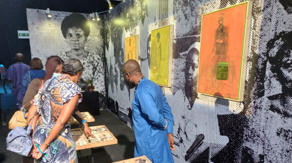 An artist at Art X Lagos explains his work to a visitor looking at his work