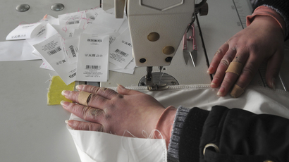 An employee sews a piece of cloth at a garment factory