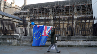 An anti-Brexit protester carries flags past the Houses of Parliament in London, Britain, December 11, 2018.