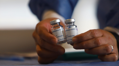 A healthcare worker holds empty vials of the Oxford/AstraZeneca coronavirus disease vaccine. Scientists behind the medication have launched a phase 1 trial to test a new vaccine against plague.