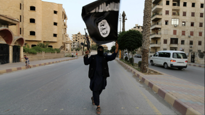 A member loyal to the Islamic State in Iraq and the Levant waves an ISIL flag in Raqqa, June 29, 2014.
