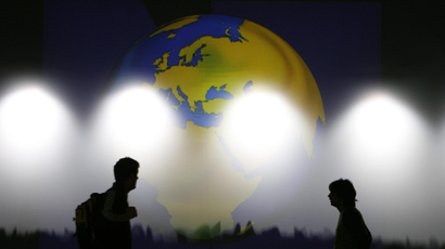 Volunteers walk in front of a projection of the globe as they prepare the main stage for the WEF in the Swiss Alpine resort town of Davos