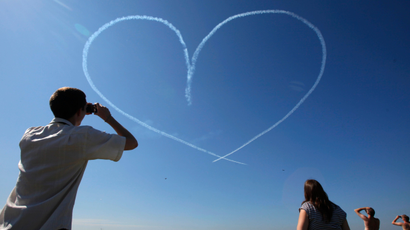 People look at a heart created by smoke from the L-39 jets of the "Russ" aerobatic team