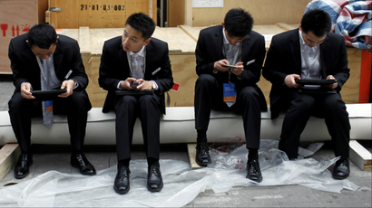 A row of people looking at their smartphones and tablets