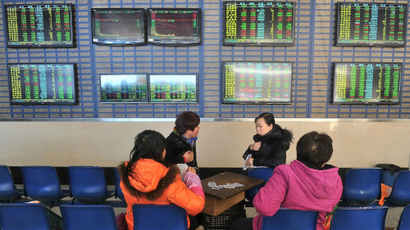 Investors play cards in front of a screen showing stock information at a brokerage house in Hefei, Anhui province, January 19, 2015. China stocks suffered their biggest one-day percentage drop in more than six and a half years, dragged down by record tumbles in financial stocks as authorities battled excessive market speculation.