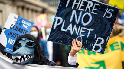 A demonstrator wearing a mask holds a banner during a protest, as the UN Climate Change Conference (COP26) takes place, in London