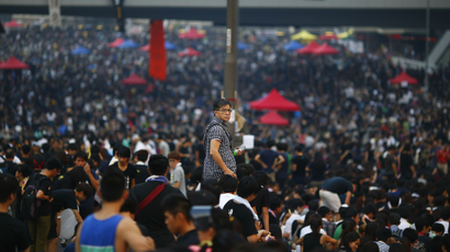 A man looks at the protesters around him as they block the main street to the financial Central district, outside the government headquarters in Hong Kong, September 30, 2014