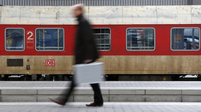 A businessman walks in front of a Deutsche Bahn train in Berlin