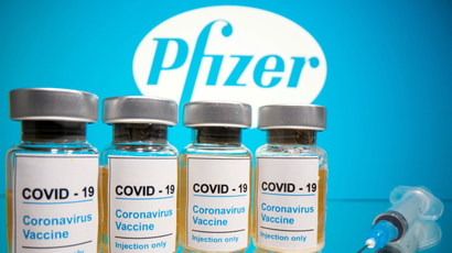 Vials with a sticker reading, "COVID-19 / Coronavirus vaccine / Injection only" and a medical syringe are seen in front of a displayed Pfizer logo in this illustration taken October 31, 2020.