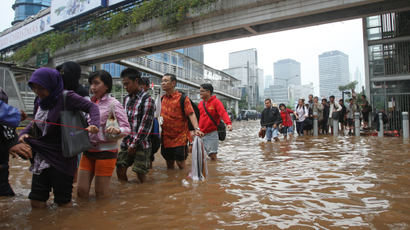 People wade through a flooded street in Jakarta