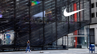 People wearing protective face masks walk past the closed Nike store on a nearly empty 5th Avenue
