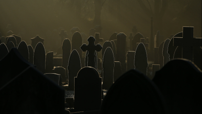 Sunlight glints off frost-covered gravestones in a cemetery in Altrincham, northern England.