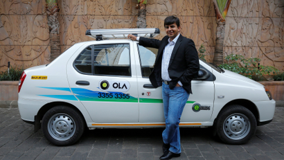 Bhavish Aggarwal, CEO and co-founder of Ola, an app-based cab service provider, poses in front of an Ola cab in Mumbai