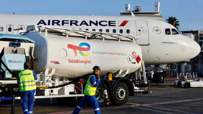 Ground crew workers in hi-viz vests fill an Air France plane with sustainable aviation fuel.