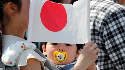 A baby holds a Japanese national flag outside the Imperial Palace