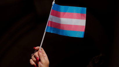 A hand holding a blue, pink, and white trans flag