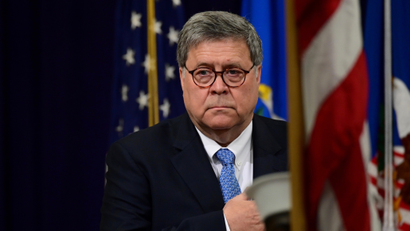 AG Bill Barr with his hand on his heart near the US flag.