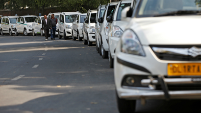 Drivers of Uber and Ola walk next to their parked vehicle's during a protest in New Delhi