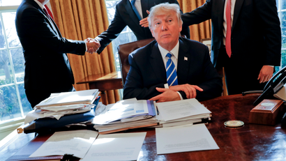 President Donald Trump sits at his desk after a meeting with Intel CEO Brian Krzanich, left, and members of his staff in the Oval Office of the White House in Washington, Wednesday, Feb. 8, 2017.