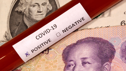 Picture illustration of a test tube labelled with the coronavirus placed on U.S. dollar and yuan banknotes