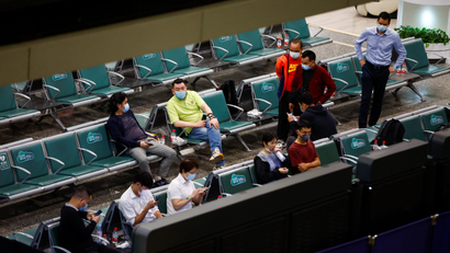 People sit on green chairs in an airport waiting area following news that an airplane crashed in Wuzhou.