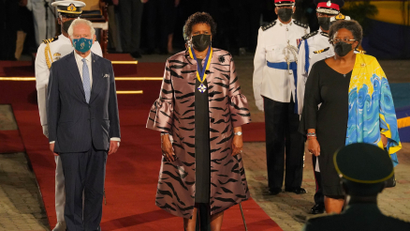 Britain's Prince Charles is joined by Barbados President Sandra Mason and Barbados Prime Minister Mia Mottley on a red carpet at a ceremony to celebrate the Republic's separation from the monarchy. Soldiers are flanked on either side of them.