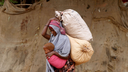 A displaced Somali woman carries a child and her belongings as she arrives at a temporary dwelling after fleeing famine in the Marka Lower Shebbele regions to the capital Mogadishu, September 20, 2014. The United Nations said this month more than a million people in war-ravaged Somalia were struggling to meet daily nutritional needs. The roughly 130,000 people displaced from their homes this year alone are bearing the brunt of the crisis.
