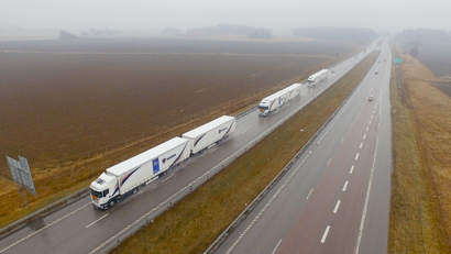 Three Scania trucks in a column formation on a highway
