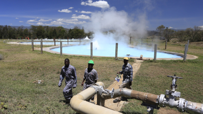Workers walk near a hot spring at the Olkaria Geothermal power plant